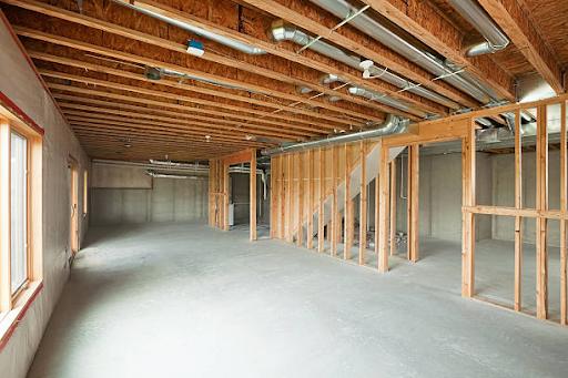 An unfinished walk-out basement in a large two-story or ranch house
