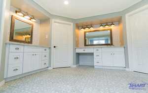 Beautiful white bathroom features with gray marble tops vanities with flank a wood mirrors